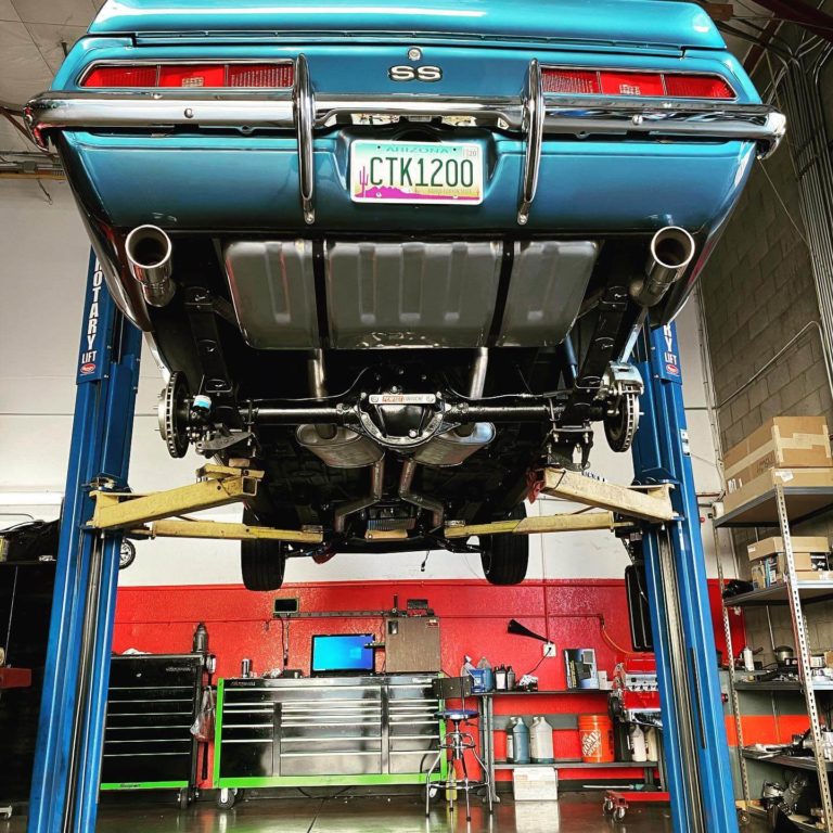 The underneath of a classic car that is hoisted up on a car lift
