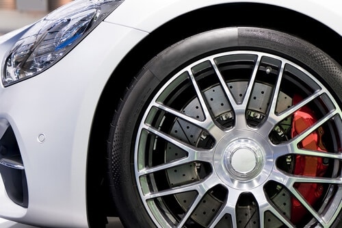 Ready to Boost Your Stopping Power with Wilwood Brakes? Call Ace Performance Automotive in Gilbert AZ; closeup image of performance brakes seen through rims of white sports car