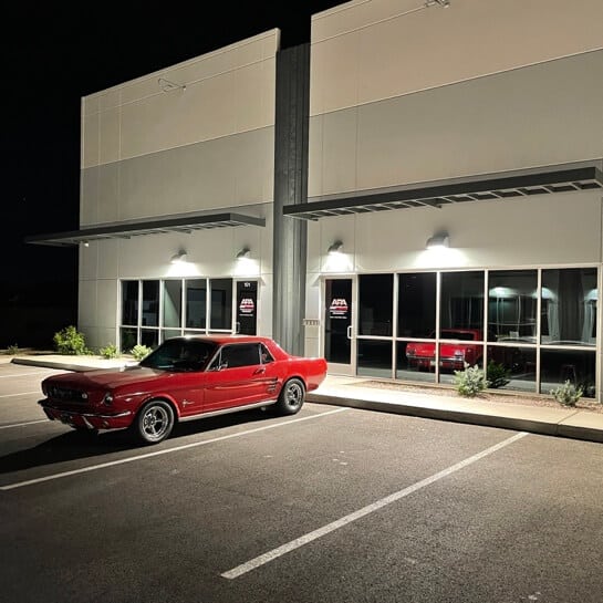 Outside Ace Performance Automotive in Queen Creek, AZ at night time with outside lights on and remodeled red 70's mustang