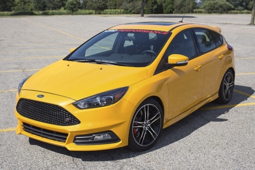 2015 FORD FOCUS ST BUILD USING COBB STAGE 3 TUNING PACKAGE with Ace Performance Auto in Gilbert and Queen Creek AZ, image of yellow 2015 Ford Focus ST in parking lot with Ford Performance sticker on top of outside windshield in white and red