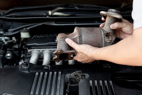 The Most Expensive Auto Repairs And How to Avoid Them | Ace Performance Auto in Gilbert, AZ. Closeup image of an old catalytic converter in the hands of an auto technician.
