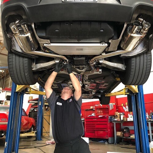 Preventative Maintenance in Gilbert, AZ | Ace Performance Automotive. Image of a mechanic under a suspended car doing preventative maintenance. 