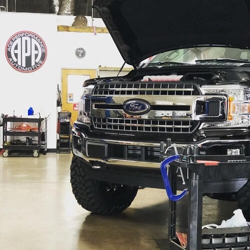 Preventative Maintenance in Gilbert, AZ | Ace Performance Automotive. Image of a black Ford vehicle with hoods up. The vehicle is inside Ace Performance’s auto shop garage.
